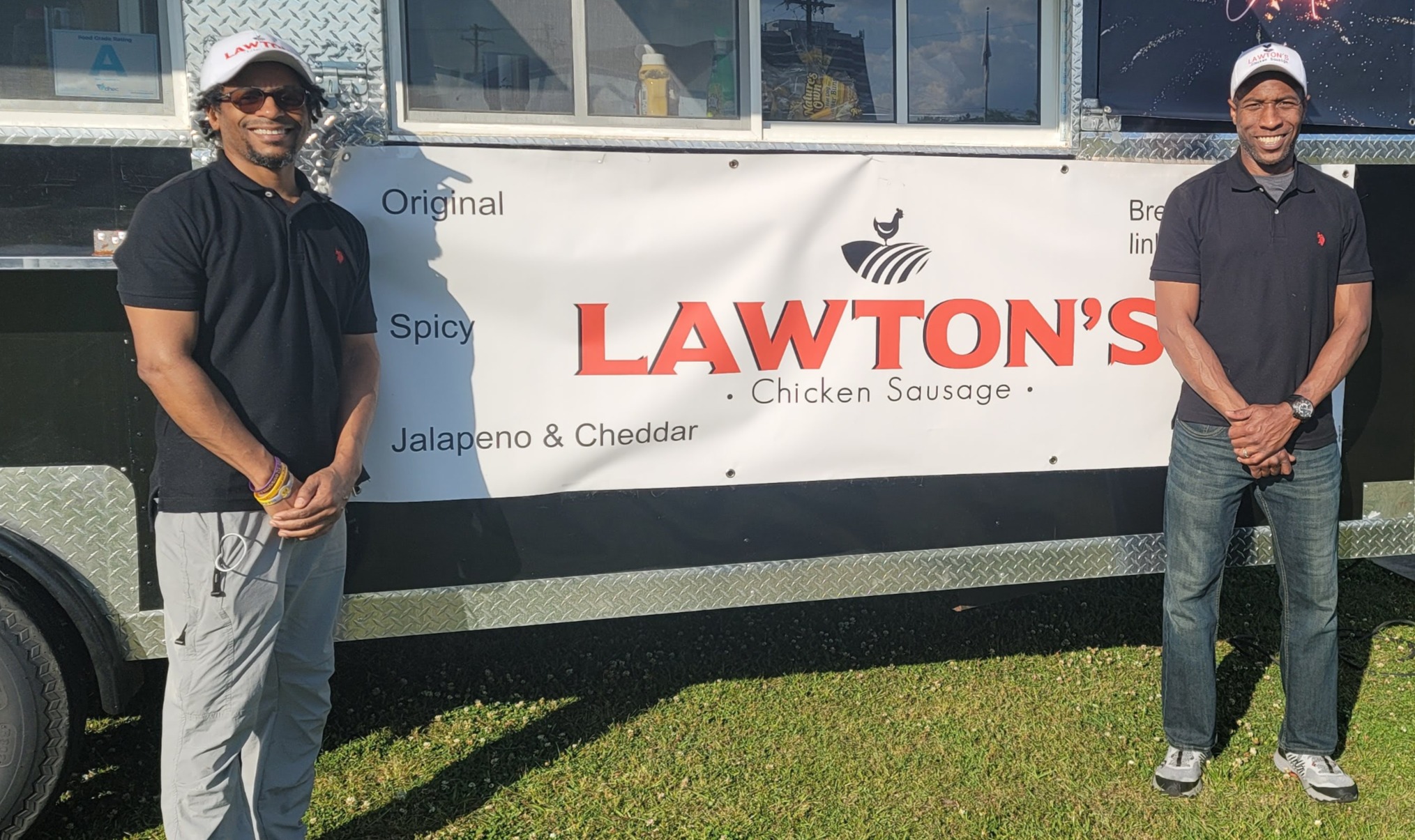 The two founders standing beside the Lawton's Chicken Sausage trailer